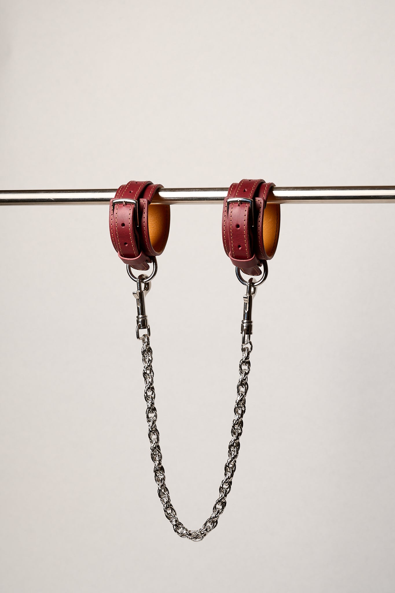 Red leather cuffs with chains on a white background