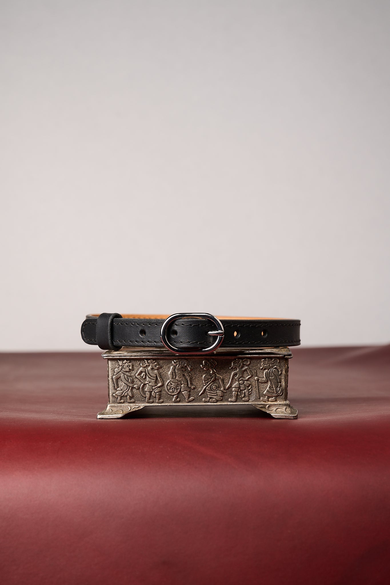Black leather collar with decorative buckle on a textured surface