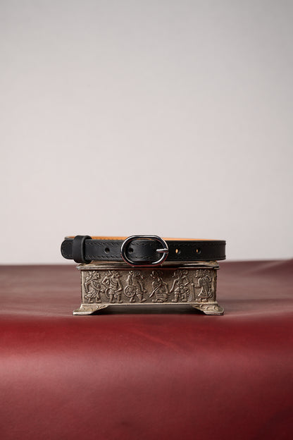 Black leather collar with decorative buckle on a textured surface