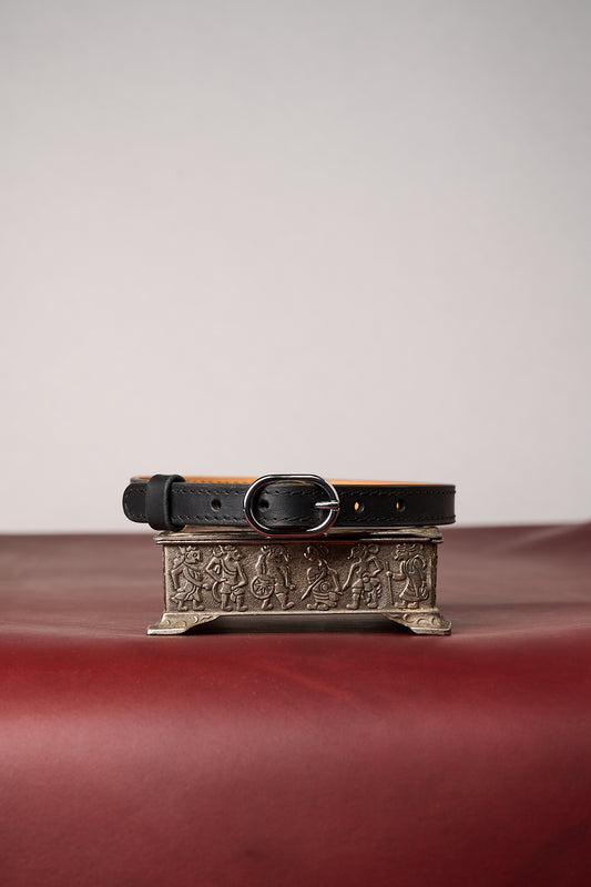 Black leather collar with decorative buckle on a textured surface