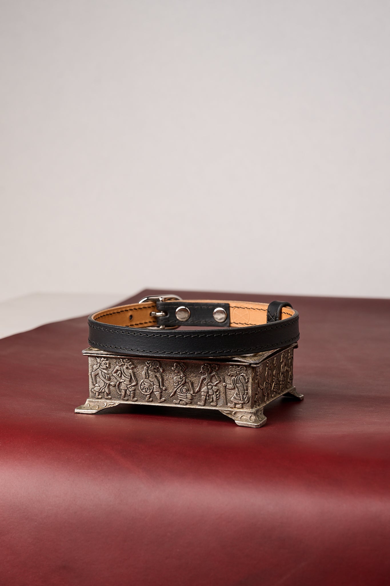 Black leather collar with decorative buckle on a red background