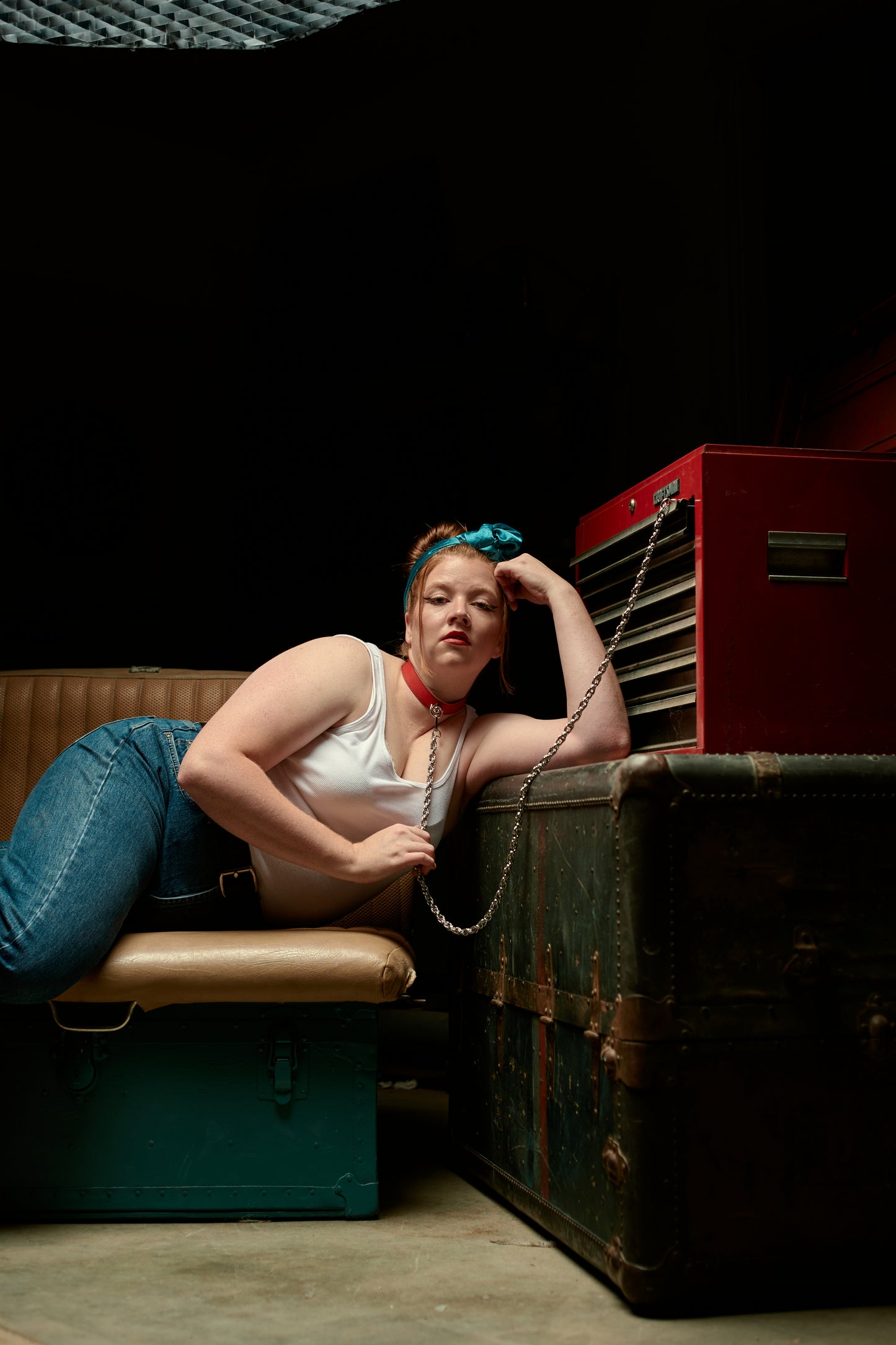 Woman sitting on a bench with a red necklace and long chain attached to toolbox.