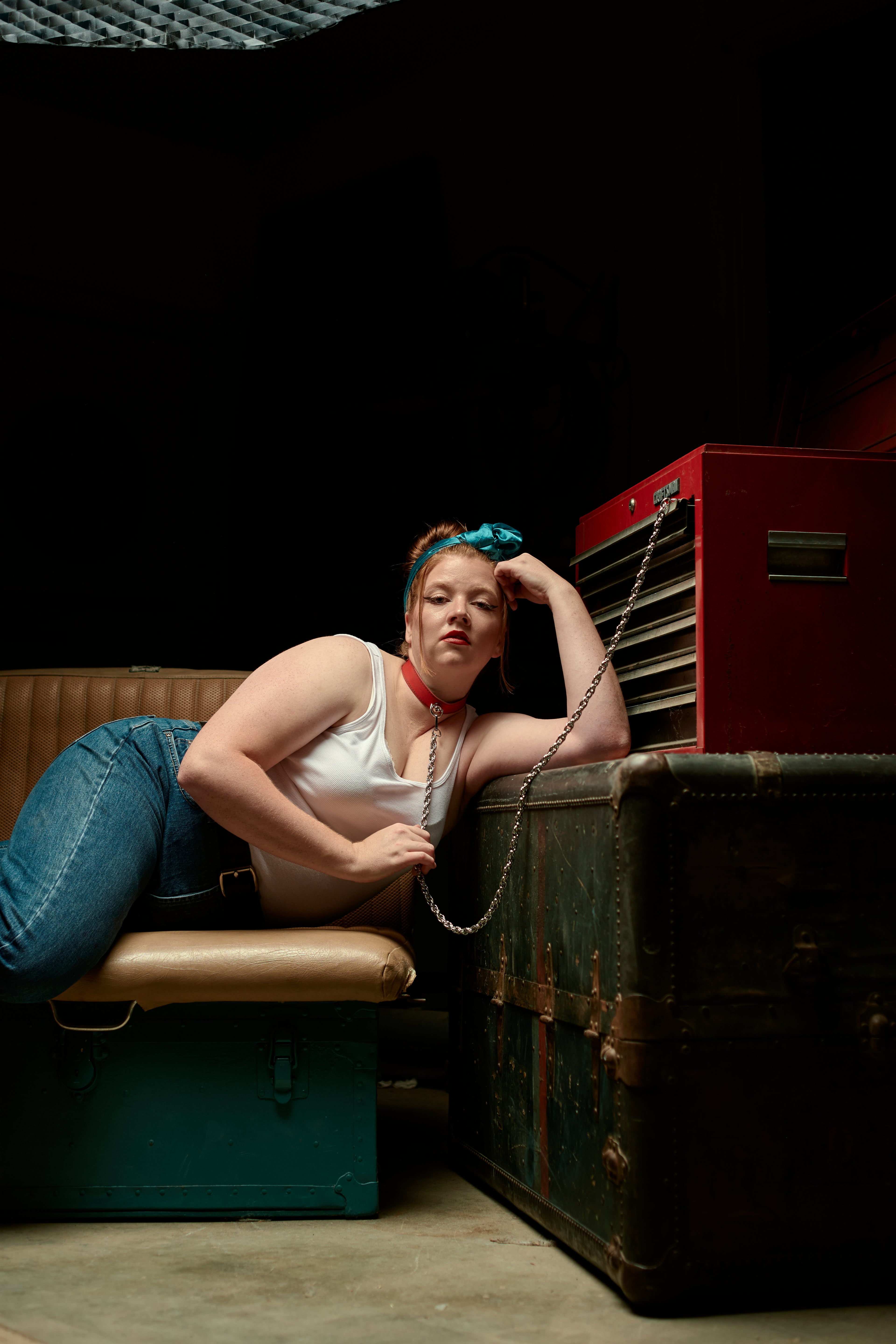 Woman sitting on a bench with a red necklace and long chain attached to toolbox.