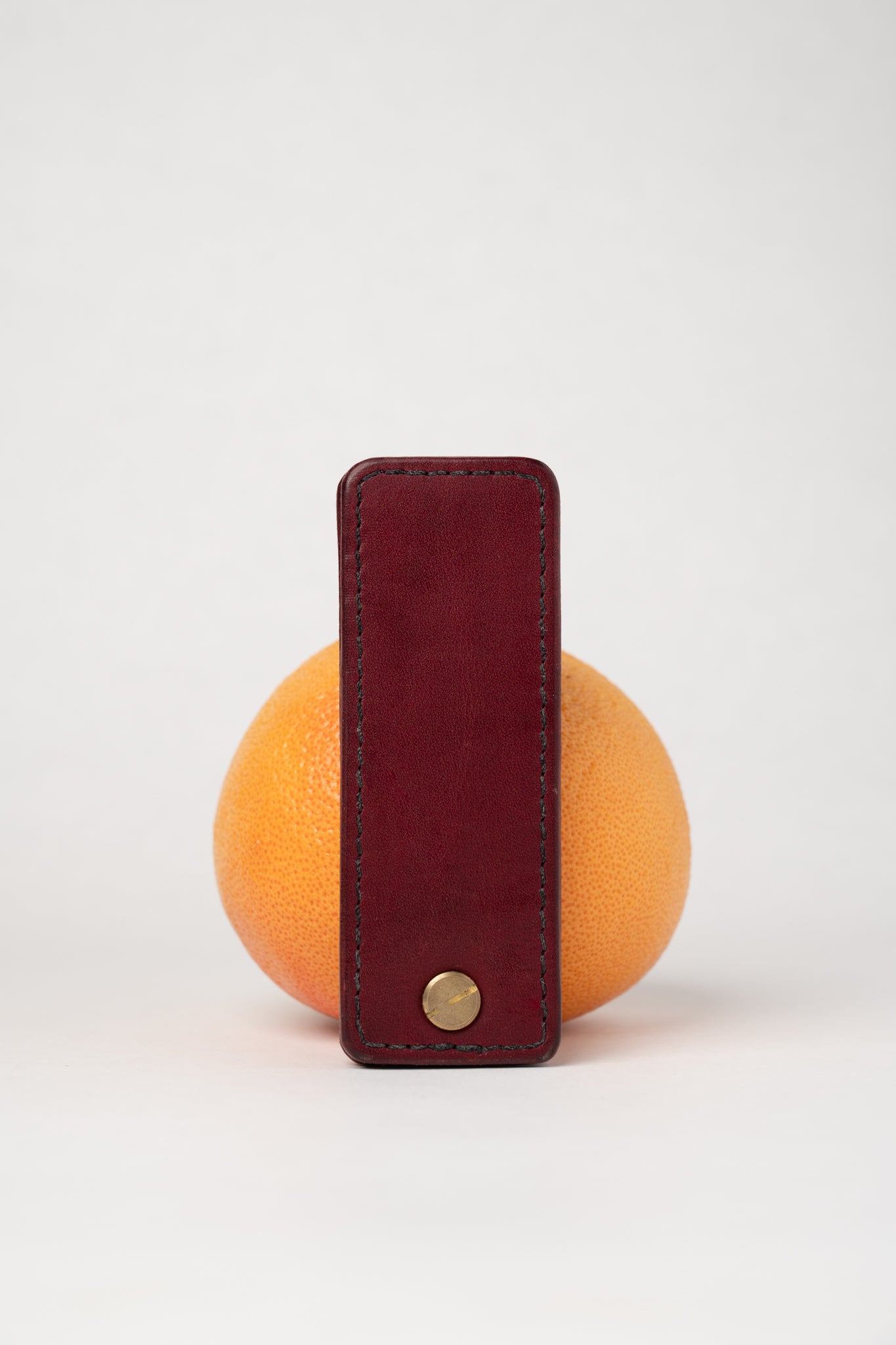 Burgundy leather portable pocket paddle with brass rivets and black thread.