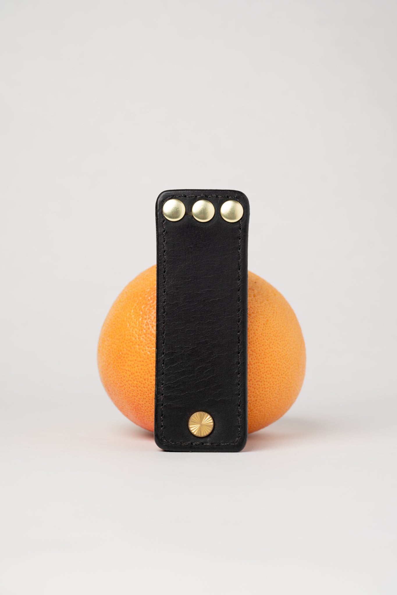 Black leather portable pocket paddle with brass rivets and black thread.