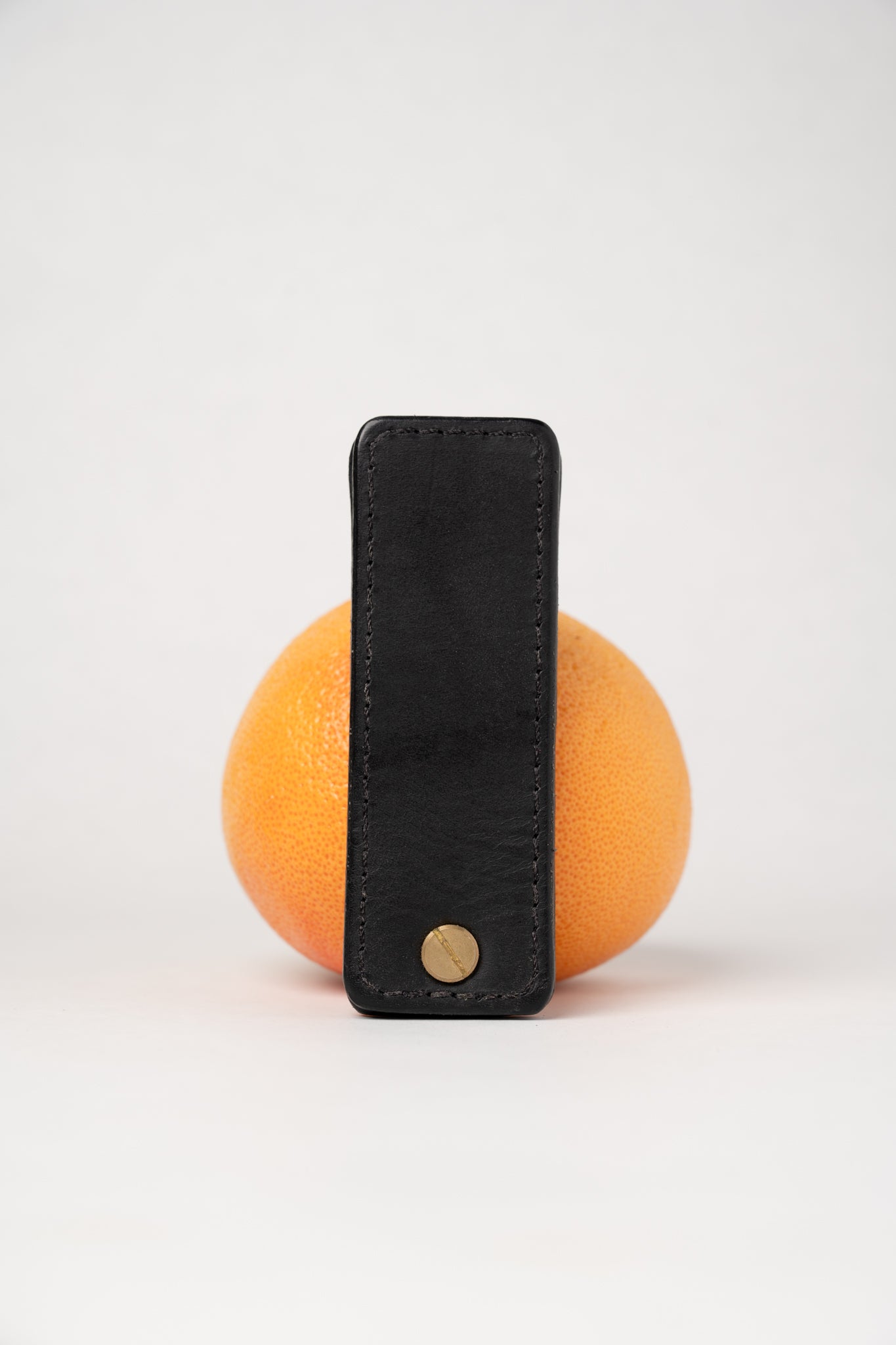 Black leather portable pocket paddle with brass rivets and black thread.