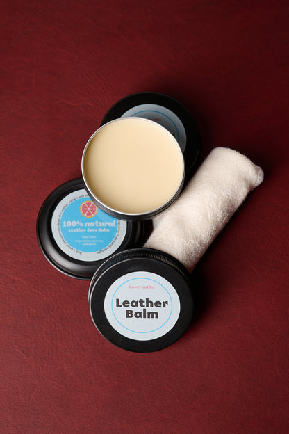 Natural handmade leather conditioning balm with applicator cloth on a red background